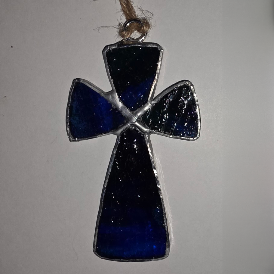 Stained glass cross ornament in deep midnight blue with silver solder and twine hanger.