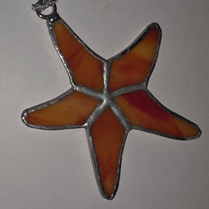 Stained glass starfish pendant in warm sunset colors with silver solder lines.